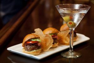 An attractive presentation of sliders, chips and a martini. Courtesy of Palm Restaurant.